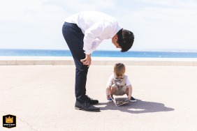 In Nice, the bride and groom's son looks at a book during group photos, creating a minimalist scene under a vast sky.